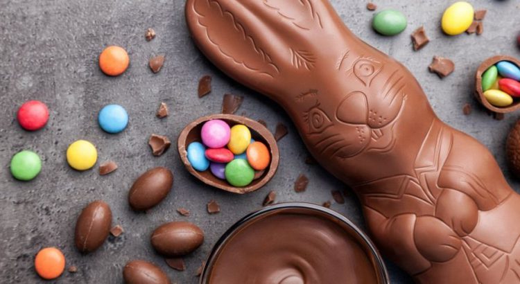 Chocolate Easter candy spread out on a table including a milk chocolate bunny and small colorful candy pieces